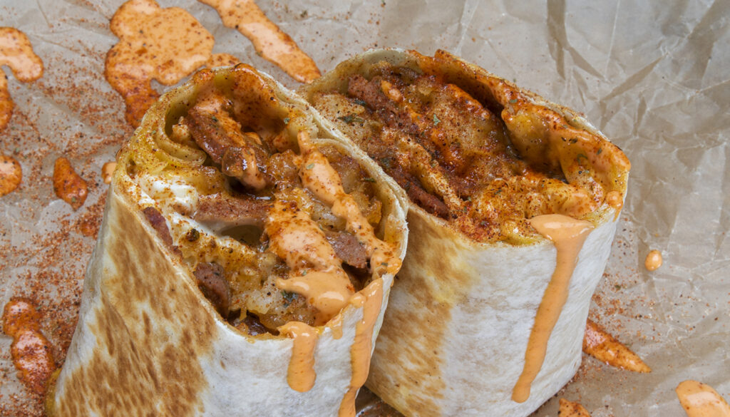 Würst Burrito - 3 eggs, choice of haus sausage, white american cheese, crispy tater tots, caramelized onions, spicy mayo; sides of spicy mayo & hot sauce